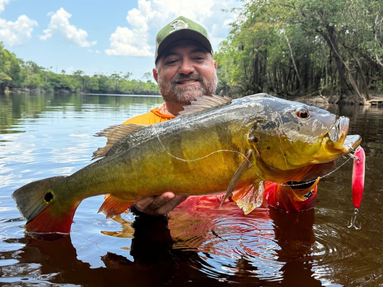 Pescador com tucunaré em uma embarcação na Amazônia